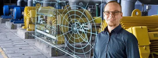 A man in a plaid shirt and glasses stands among yellow machinery in an industrial setting, with a digital, radar-like display overlaid.